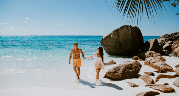 http://Couple%20walking%20on%20the%20beach%20during%20a%20luxury%20Seychelles%20honeymoon
