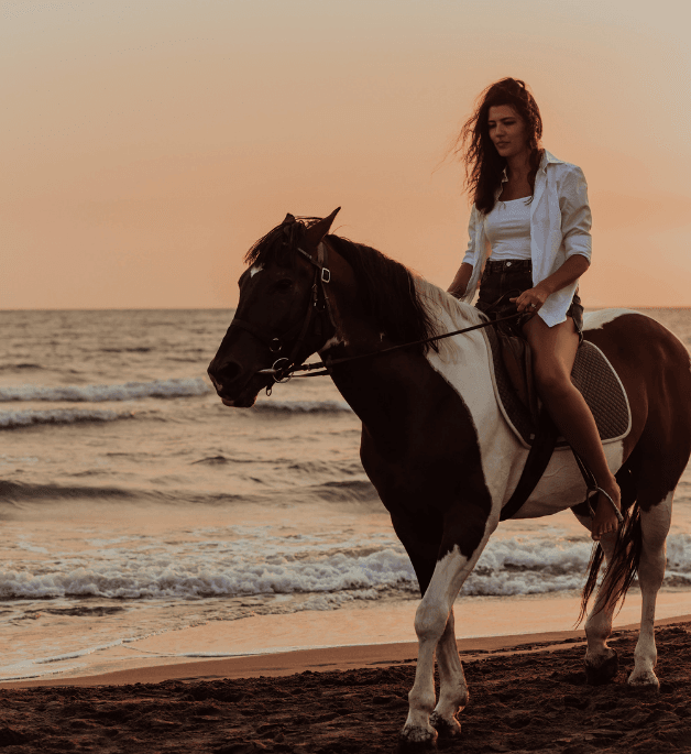 Woman riding a white horse on the beach during an Essaouira excursion from Marrakech